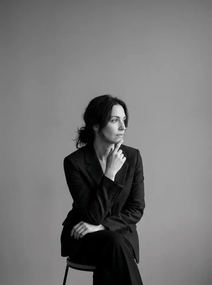 Retrato en blanco y negro de una mujer con americana sentada, mirada pensativa.